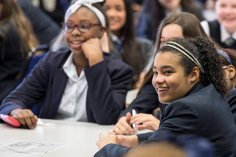 Group of smiling students looking engaged in a secondary school classroom
