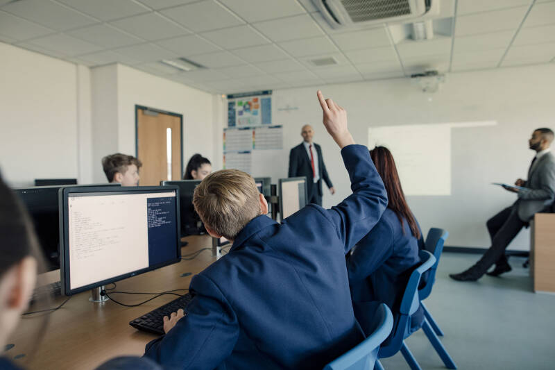 Student raises hand in a school classroom