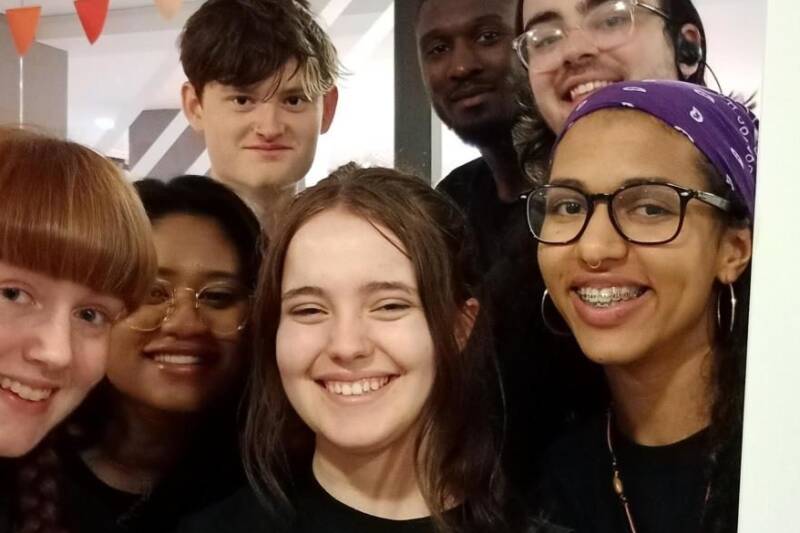 Seven young people smile into the camera