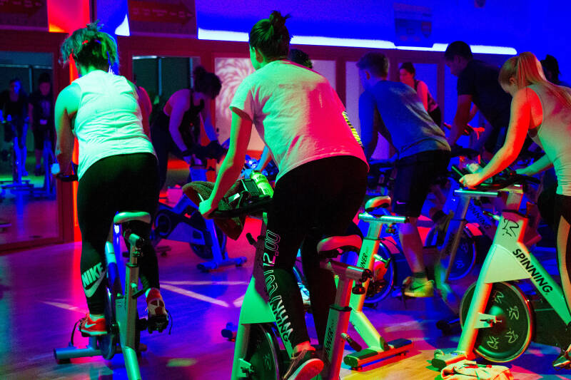 Football player attempts to keep the ball away from an opposition player during a match on a grass football pitch